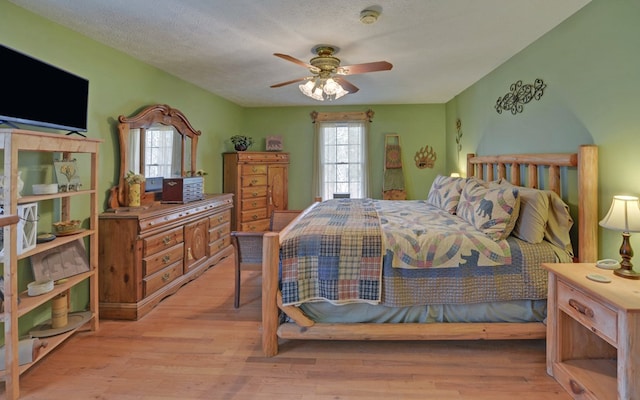 bedroom with multiple windows, a textured ceiling, and light wood-type flooring