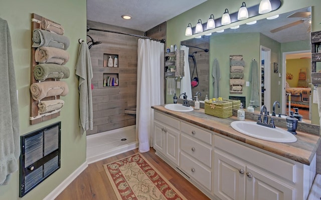 bathroom with heating unit, hardwood / wood-style floors, vanity, walk in shower, and a textured ceiling