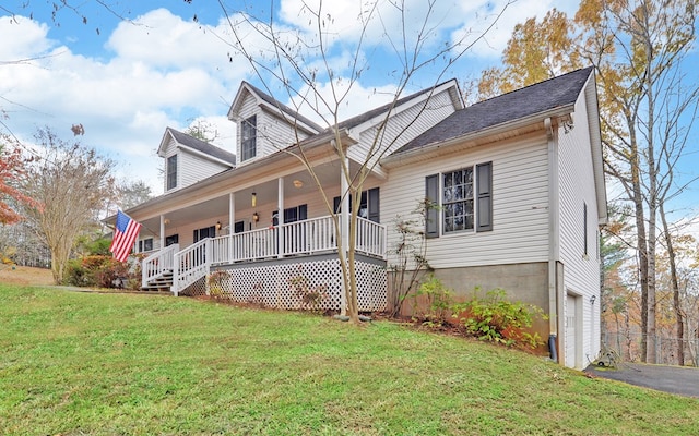 view of front of house featuring a garage, covered porch, and a front lawn