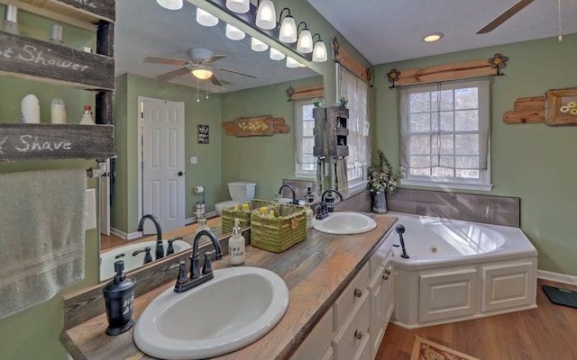 bathroom with a washtub, ceiling fan, vanity, wood-type flooring, and toilet