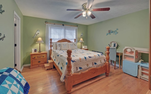 bedroom featuring ceiling fan, light hardwood / wood-style flooring, and a textured ceiling