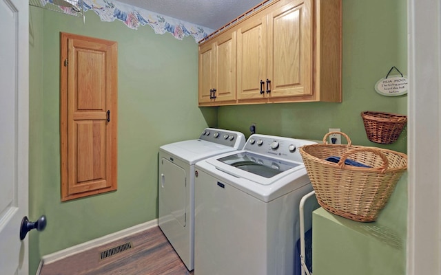 laundry area with dark hardwood / wood-style floors, washing machine and dryer, cabinets, and a textured ceiling