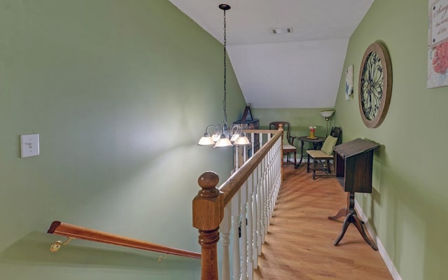 staircase featuring an inviting chandelier, lofted ceiling, and hardwood / wood-style floors