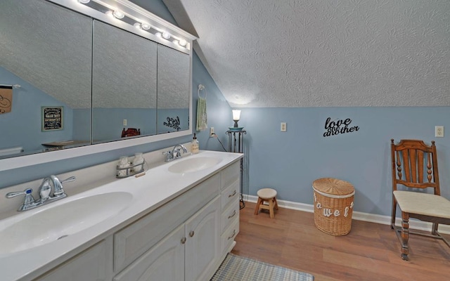 bathroom featuring lofted ceiling, hardwood / wood-style floors, a textured ceiling, and vanity