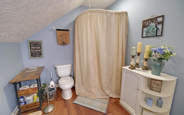 bathroom featuring lofted ceiling, toilet, hardwood / wood-style floors, and a textured ceiling