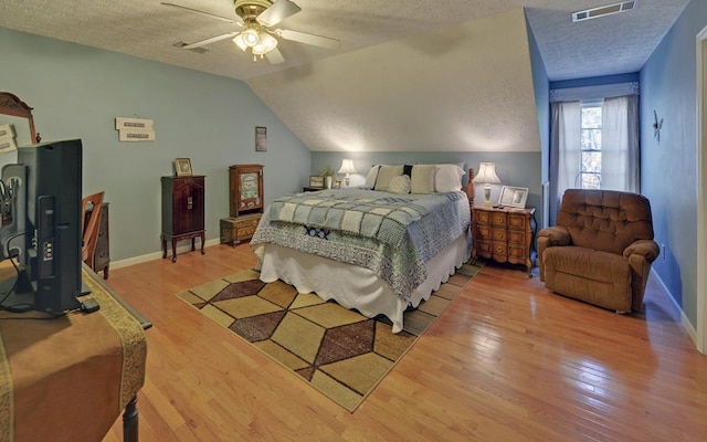 bedroom with ceiling fan, hardwood / wood-style flooring, vaulted ceiling, and a textured ceiling