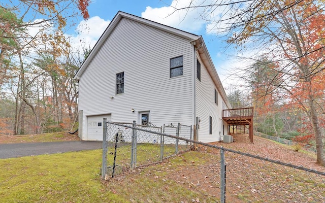 view of side of home with cooling unit, a garage, a yard, and a deck