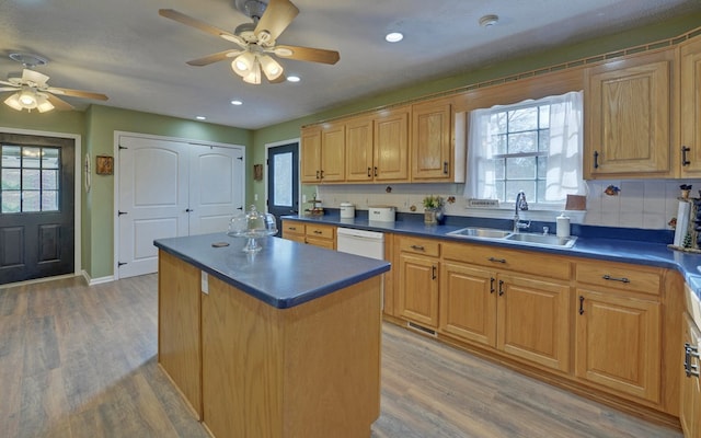 kitchen featuring sink, a center island, light wood-type flooring, white dishwasher, and decorative backsplash