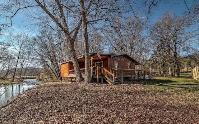 back of property featuring a deck with water view and a yard