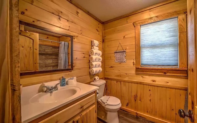 bathroom featuring vanity, hardwood / wood-style flooring, toilet, curtained shower, and wood walls