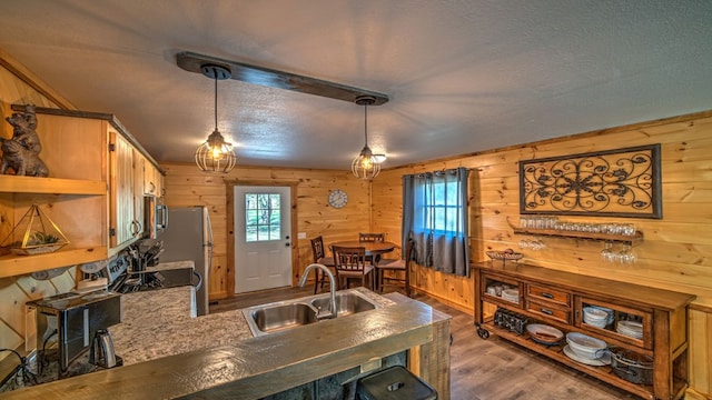 kitchen with pendant lighting, sink, wooden walls, dark hardwood / wood-style floors, and kitchen peninsula