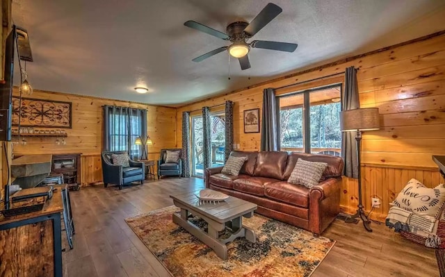 living room featuring hardwood / wood-style floors, ceiling fan, and wood walls