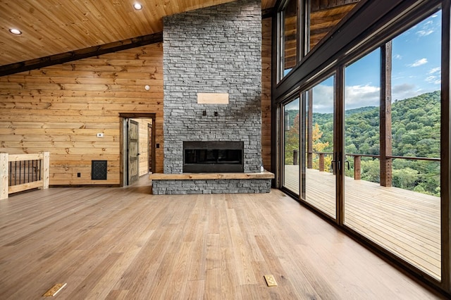 unfurnished living room with high vaulted ceiling, wood ceiling, light wood-type flooring, and a stone fireplace