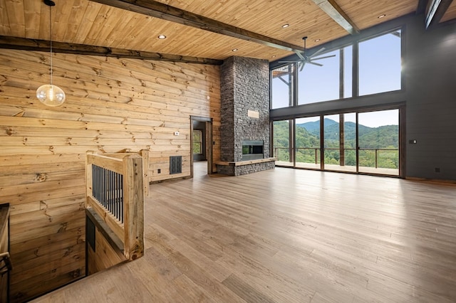 unfurnished living room featuring a stone fireplace, wood ceiling, high vaulted ceiling, a mountain view, and beamed ceiling