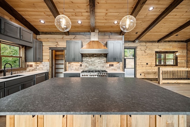 kitchen with sink, premium range hood, a spacious island, decorative light fixtures, and wooden ceiling