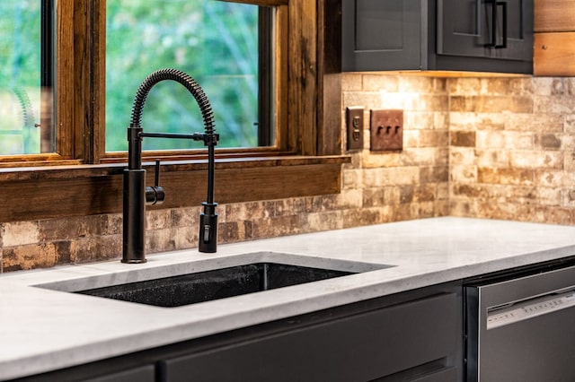 kitchen with tasteful backsplash, sink, light stone counters, and stainless steel dishwasher