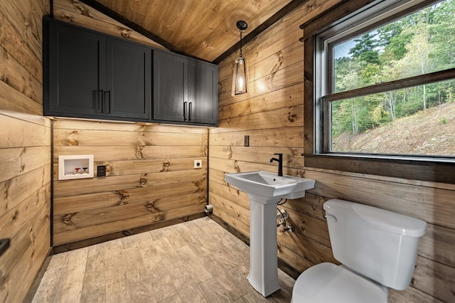 washroom with light wood-type flooring, washer hookup, wooden ceiling, and wooden walls