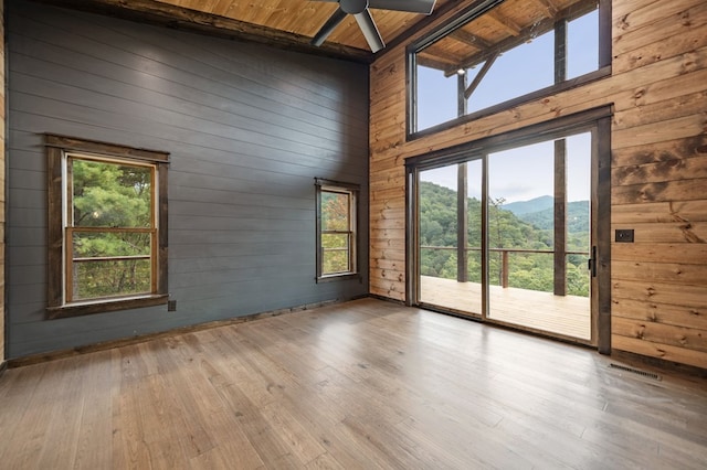 empty room with a towering ceiling, ceiling fan, wood ceiling, a mountain view, and light hardwood / wood-style flooring