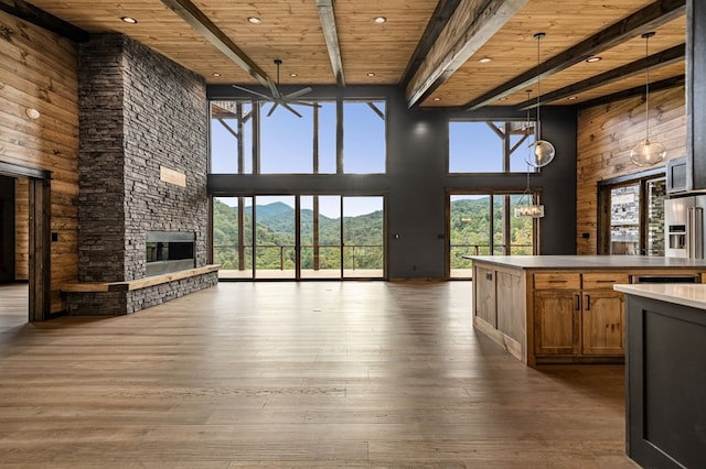 interior space featuring a stone fireplace, a high ceiling, a mountain view, dark wood-type flooring, and wooden ceiling