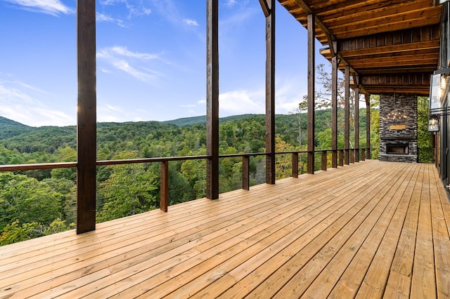 wooden terrace with an outdoor stone fireplace