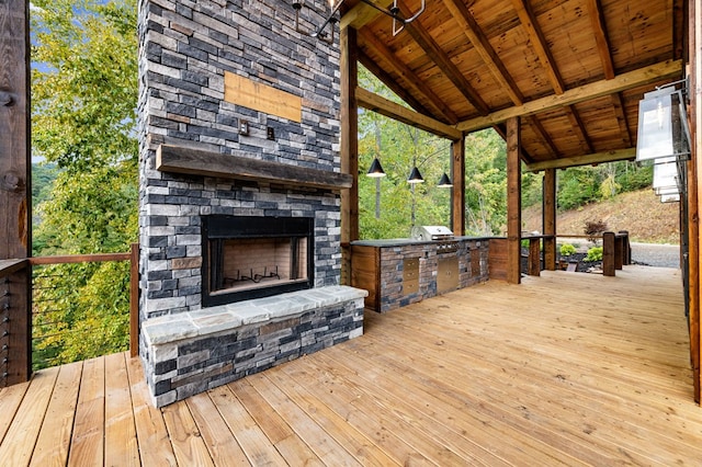 wooden deck featuring area for grilling, grilling area, and an outdoor stone fireplace