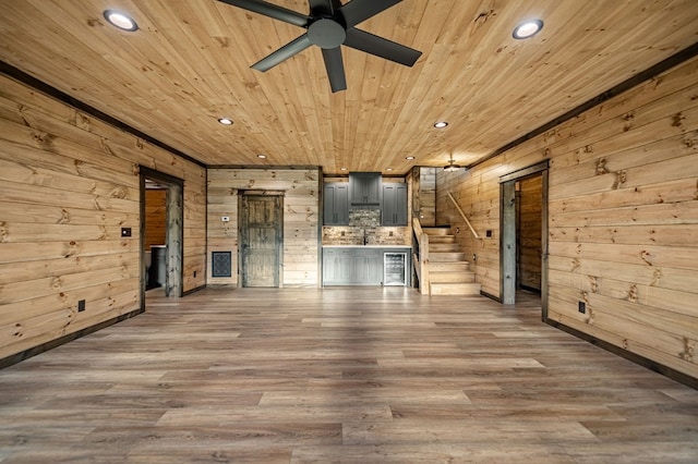 unfurnished living room with ceiling fan, wood-type flooring, wooden walls, and wooden ceiling