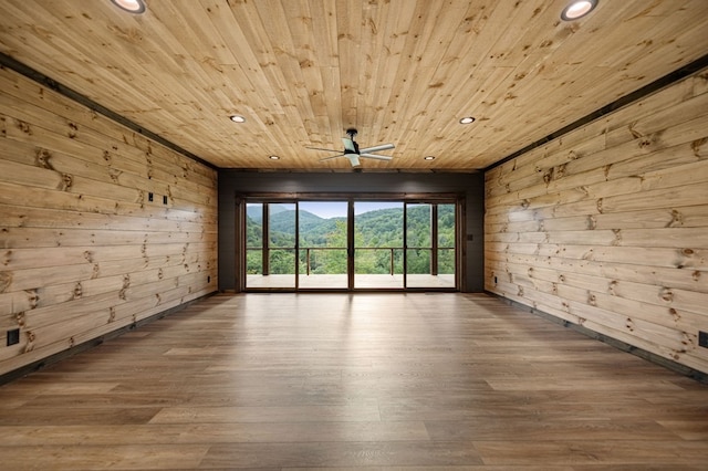 spare room with ceiling fan, wooden walls, wooden ceiling, and wood-type flooring