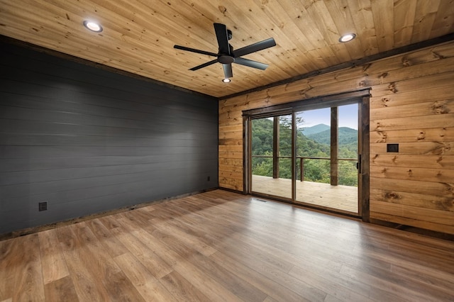 spare room featuring wood ceiling, a mountain view, light hardwood / wood-style flooring, and wood walls