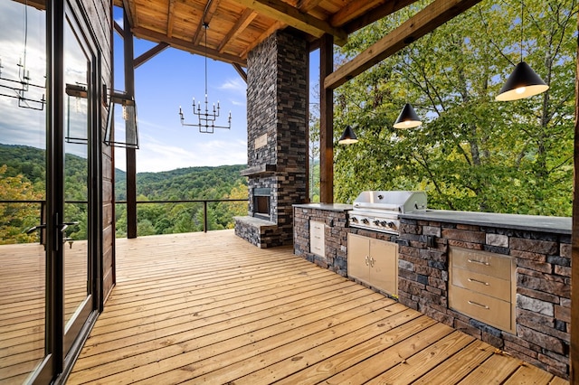 deck with area for grilling, an outdoor stone fireplace, and exterior kitchen