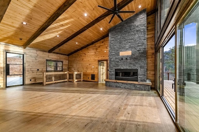 interior space featuring wood ceiling, a stone fireplace, high vaulted ceiling, and wood walls