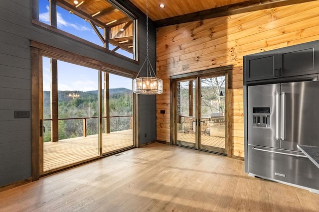 entryway with a mountain view, wooden ceiling, light wood-type flooring, and wood walls