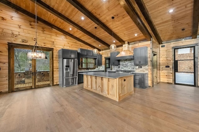 kitchen featuring custom exhaust hood, high end refrigerator, light brown cabinets, pendant lighting, and beam ceiling