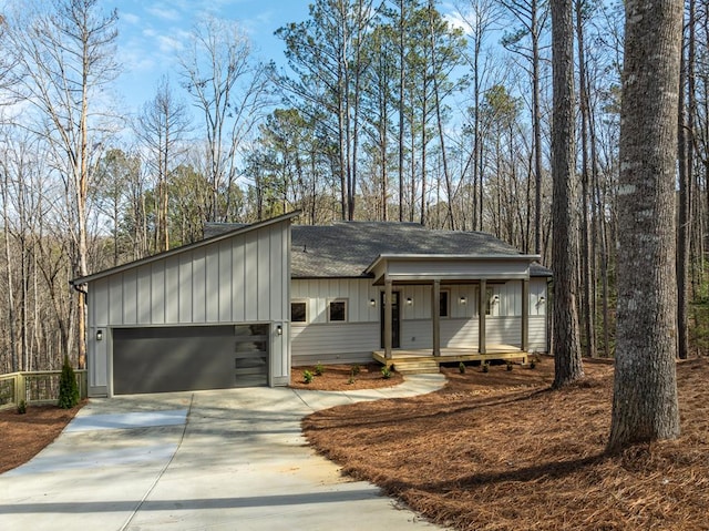 view of front of house featuring a shingled roof, concrete driveway, covered porch, an attached garage, and board and batten siding