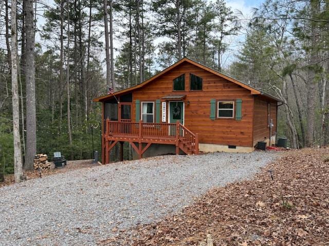 view of front facade featuring crawl space, central air condition unit, a wooded view, and gravel driveway