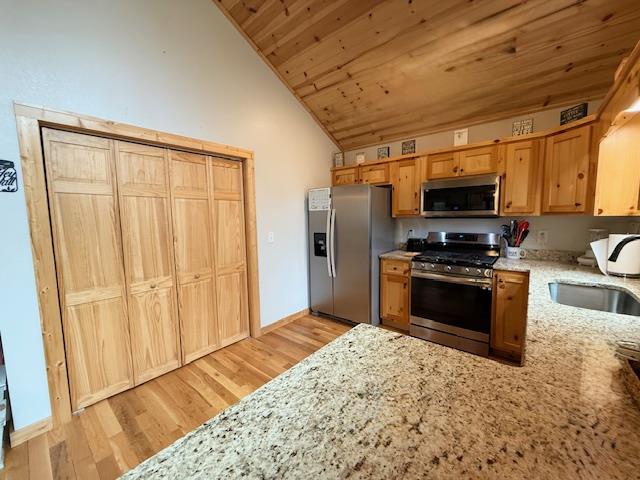 kitchen featuring light stone counters, light wood finished floors, stainless steel appliances, vaulted ceiling, and wooden ceiling