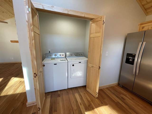 clothes washing area featuring wood finished floors, laundry area, baseboards, and separate washer and dryer