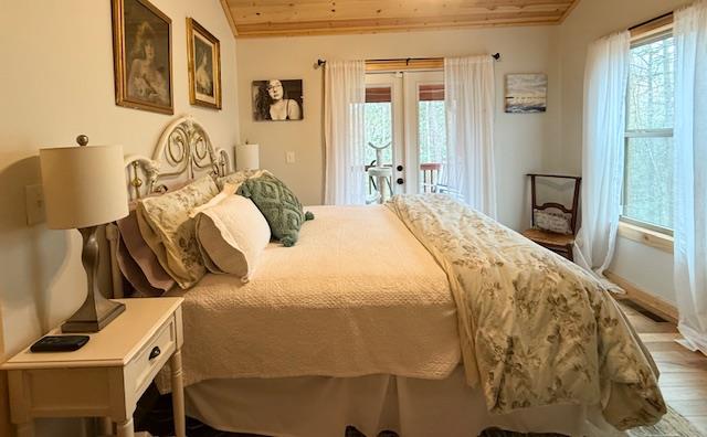 bedroom with access to outside, wood ceiling, multiple windows, and lofted ceiling