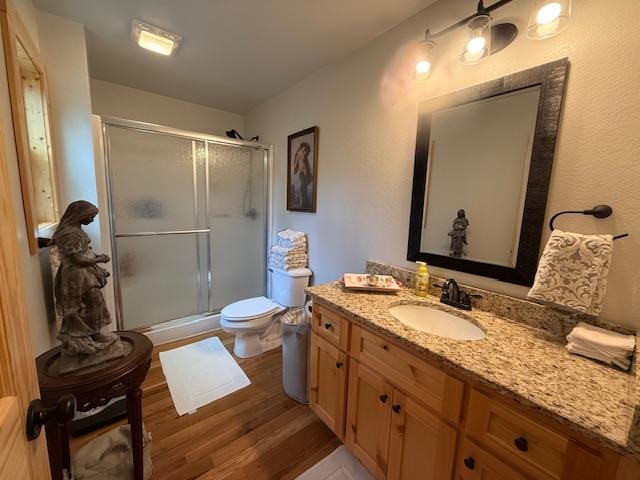 bathroom featuring vanity, wood finished floors, a shower stall, and toilet