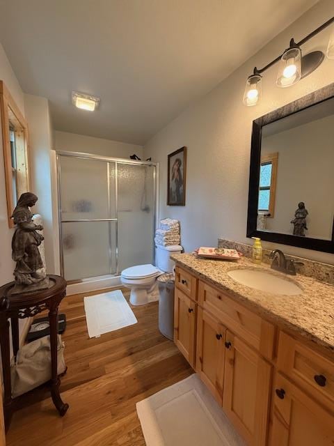 full bathroom with toilet, a shower stall, wood finished floors, and vanity