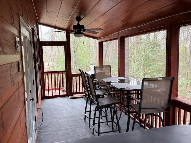 sunroom featuring wood ceiling and a ceiling fan