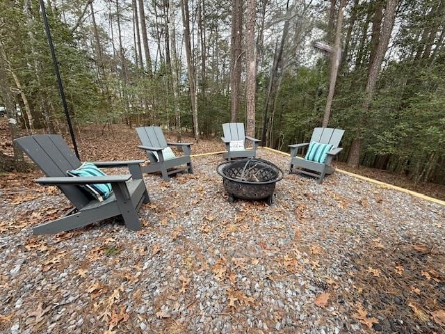 view of yard featuring an outdoor fire pit and a view of trees