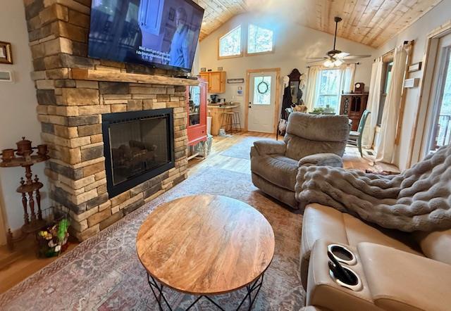 living room featuring wooden ceiling, a fireplace, vaulted ceiling, and light wood-style floors