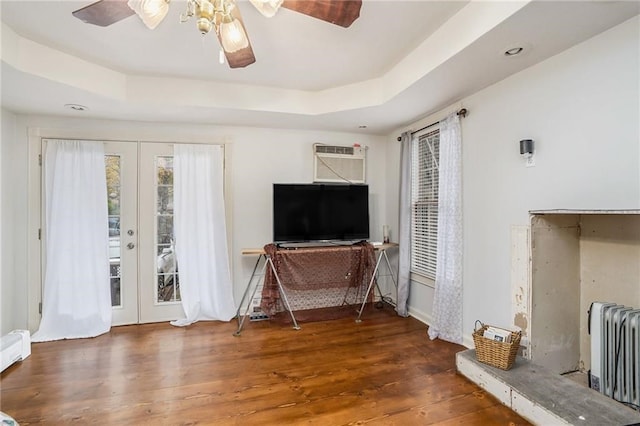 living room with radiator, ceiling fan, a tray ceiling, dark hardwood / wood-style flooring, and french doors