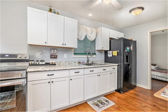 kitchen with white cabinets, stainless steel electric stove, black fridge, and sink