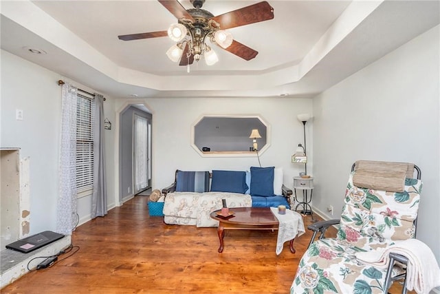 living room featuring a tray ceiling, hardwood / wood-style floors, and ceiling fan