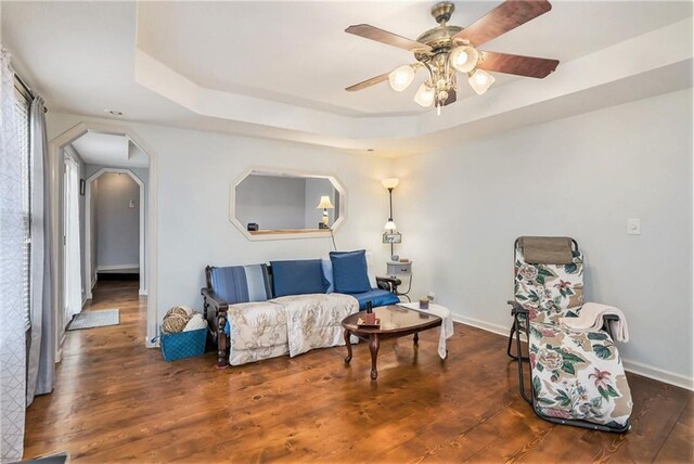 sitting room with dark hardwood / wood-style flooring, ceiling fan, and a tray ceiling