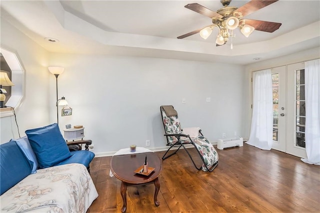 sitting room featuring dark wood-type flooring, ceiling fan, french doors, and a tray ceiling