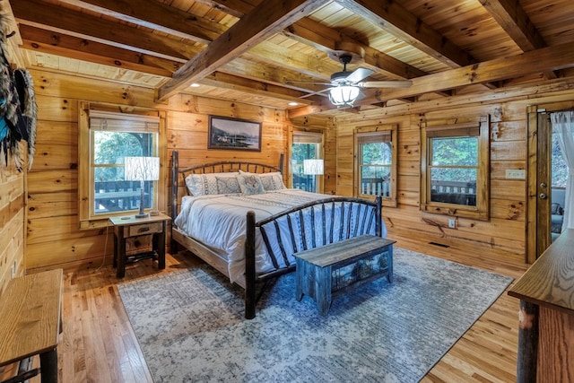 bedroom with multiple windows, wood-type flooring, wooden walls, and beamed ceiling