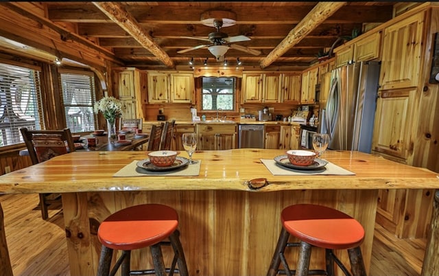 kitchen featuring sink, appliances with stainless steel finishes, a wealth of natural light, and wooden walls