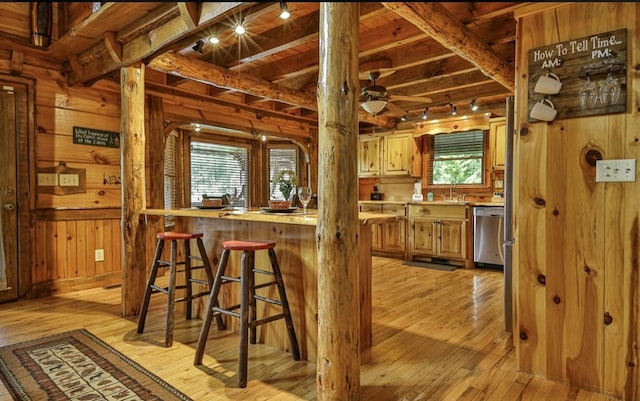 kitchen with dishwasher, wood walls, track lighting, and light hardwood / wood-style flooring